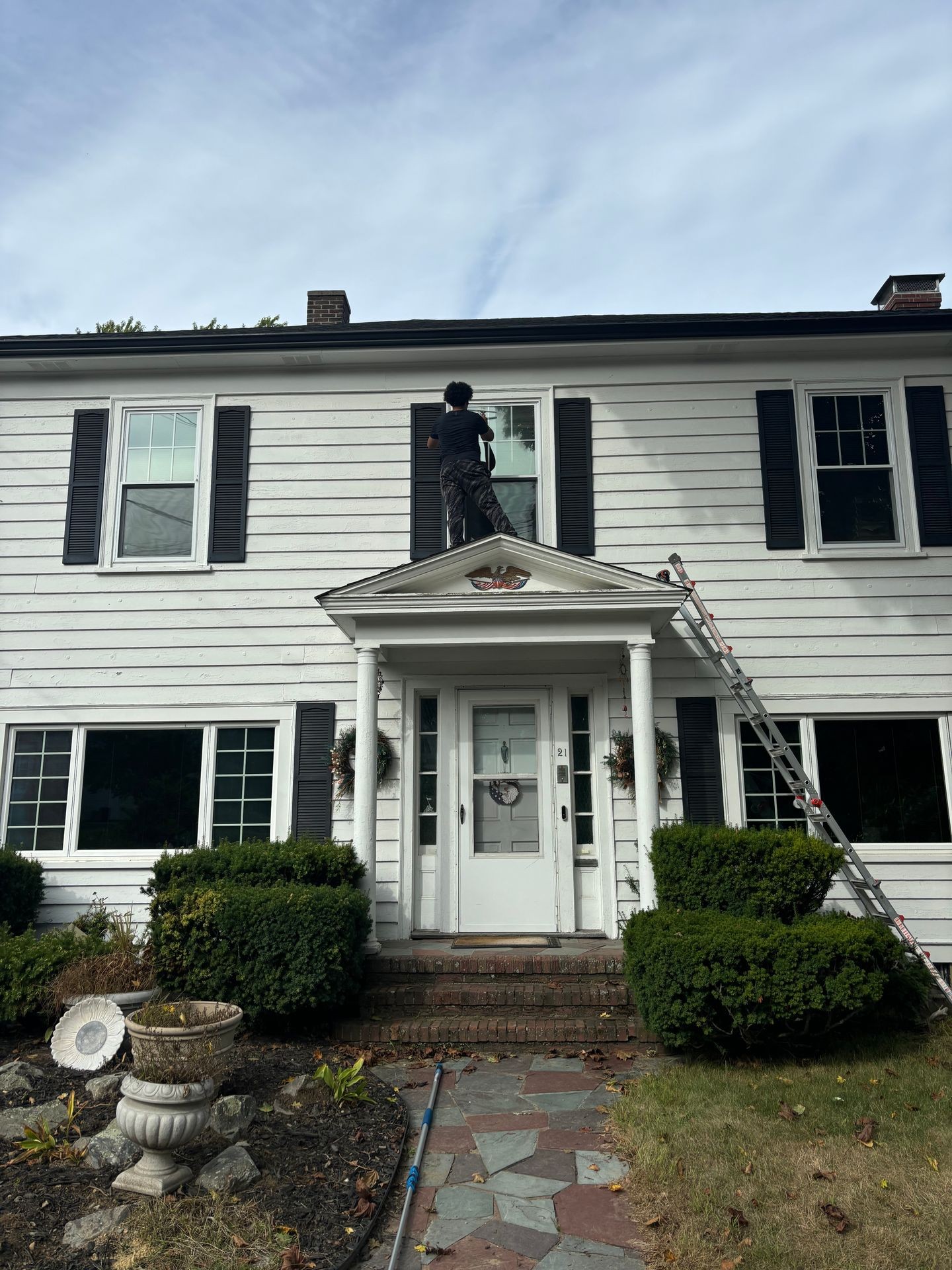 Worker washing window on a entrance roof