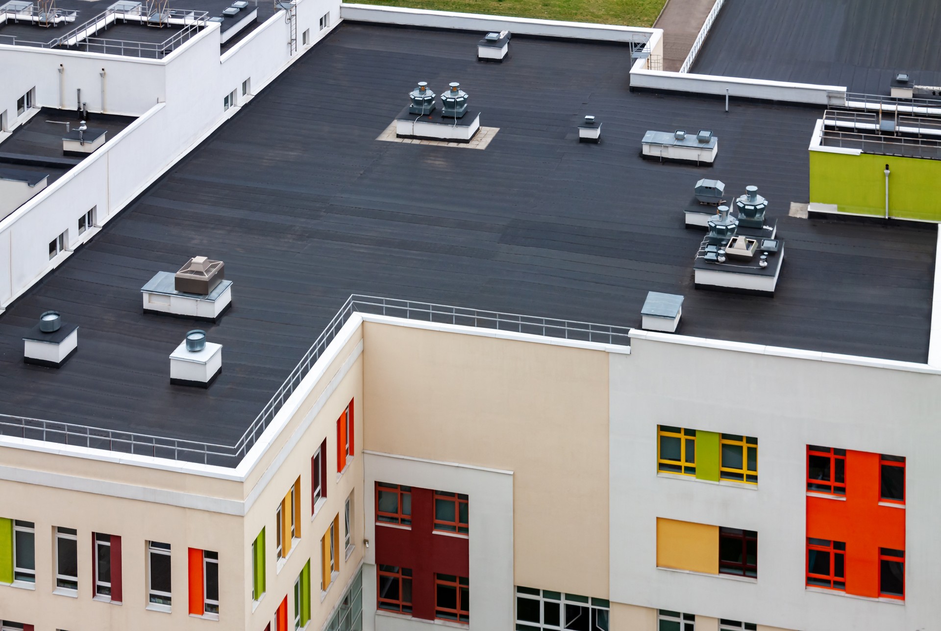 Top view dark flat roof with air conditioners and hydro insulation membranes modern apartment building residential area.